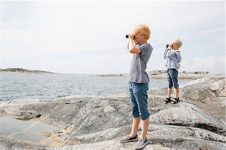 Two boys looking through binoculars on rocky seashore in the Stockholm archipelago Stock Photo - Premium Royalty-Free, Code: 6126-09102915