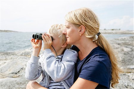 sohn - Mother and son sitting on rocky seashore, son looking through binoculars in the Stockholm archipelago Stock Photo - Premium Royalty-Free, Code: 6126-09102916