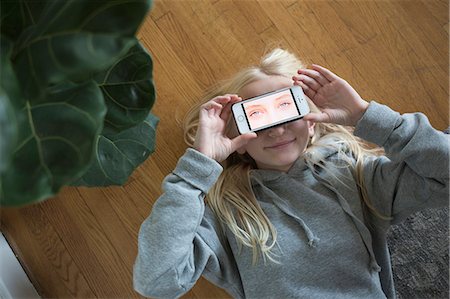 simsearch:6126-08781199,k - Girl lying on floor and covering eyes with smart phone with eyes on screen Fotografie stock - Premium Royalty-Free, Codice: 6126-09103012