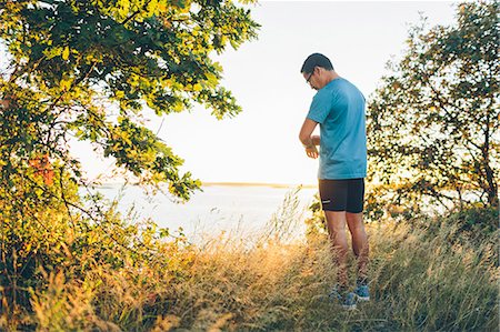 simsearch:6126-09103639,k - Mid adult man checking time while jogging at seashore Stock Photo - Premium Royalty-Free, Code: 6126-09103643