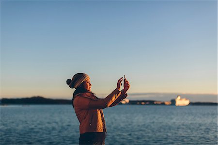 simsearch:6126-09103829,k - Woman holding a smart phone by the sea Stock Photo - Premium Royalty-Free, Code: 6126-09103681