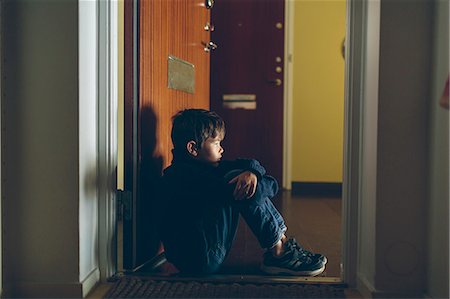 Boy sitting on floor next to door Photographie de stock - Premium Libres de Droits, Code: 6126-09103631