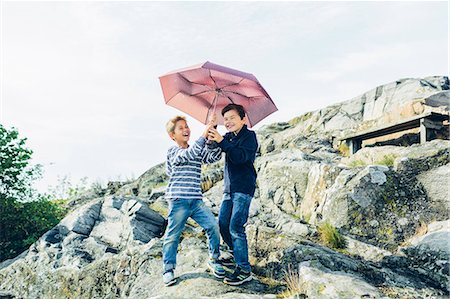 entre 8 y 9 años - Laughing boys with umbrella on rocky hill Foto de stock - Sin royalties Premium, Código: 6126-09103635
