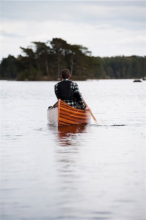 simsearch:6126-09102797,k - Man paddling canoe on lake Foto de stock - Royalty Free Premium, Número: 6126-09103731