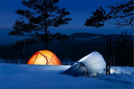 Illuminated tents on snow with forest covered mountain in background Stock Photo - Premium Royalty-Free, Code: 6126-09103737