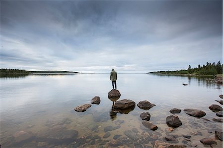 reflection (visual) - Man standing on rock by a lake in Vasterbotten, Sweden Stock Photo - Premium Royalty-Free, Code: 6126-09103841