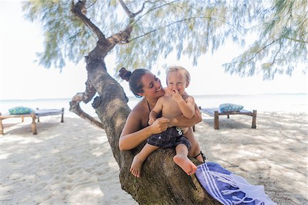 Toddler and his mother sitting on a tree at Diani Beach, Kenya Photographie de stock - Premium Libres de Droits, Code: 6126-09103892