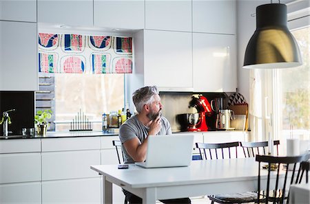 Man with laptop in kitchen Stock Photo - Premium Royalty-Free, Code: 6126-09103937