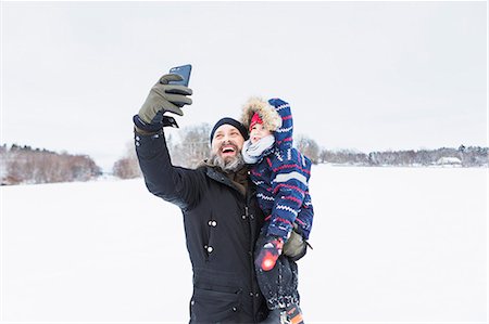 playing outdoor snow - Father taking selfie with son in snow Stock Photo - Premium Royalty-Free, Code: 6126-09103936