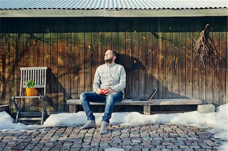 finnish people in the snow - Mid adult man sitting on bench by wooden shed Stock Photo - Premium Royalty-Free, Code: 6126-09104145