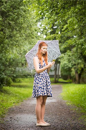 fiore dello zenzero - Woman wearing floral dress standing with umbrella in park Fotografie stock - Premium Royalty-Free, Codice: 6126-09104241