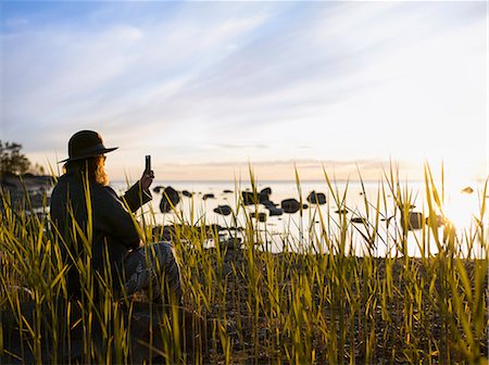 simsearch:6126-08635314,k - Woman sitting among reeds by sea and photographing Stock Photo - Premium Royalty-Free, Code: 6126-09104237