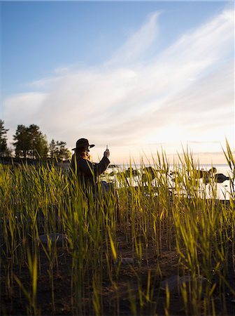 simsearch:6126-08635314,k - Woman sitting among reeds by sea and photographing Stock Photo - Premium Royalty-Free, Code: 6126-09104236