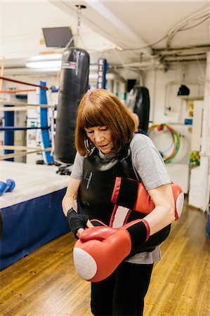 Senior woman putting on boxing gloves Foto de stock - Sin royalties Premium, Código: 6126-09104352