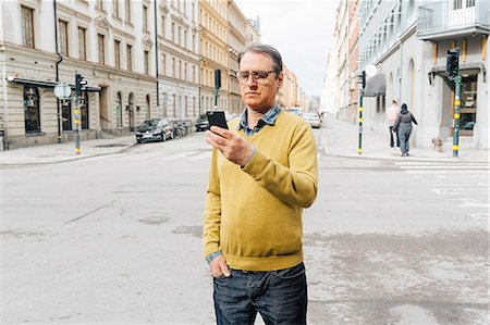 simsearch:6126-09267293,k - Man holding a smart phone on a street in Stockholm Stock Photo - Premium Royalty-Free, Code: 6126-09104314
