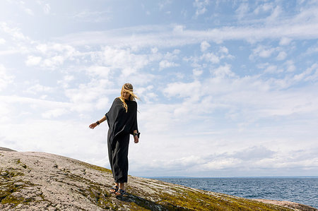 simsearch:6126-09266702,k - Windswept woman wearing black standing on rock Fotografie stock - Premium Royalty-Free, Codice: 6126-09266667