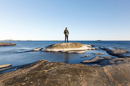 simsearch:6126-09266702,k - Man standing on rock by sea Fotografie stock - Premium Royalty-Free, Codice: 6126-09266682