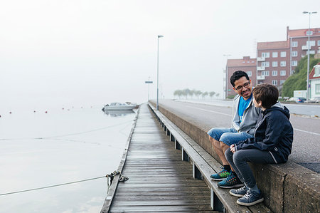 family walk path water - Father and son sitting by harbour Stock Photo - Premium Royalty-Free, Code: 6126-09267253