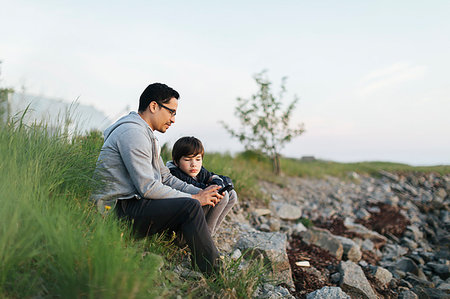 simsearch:6126-09267293,k - Father and son using a smart phone on grass Stock Photo - Premium Royalty-Free, Code: 6126-09267265