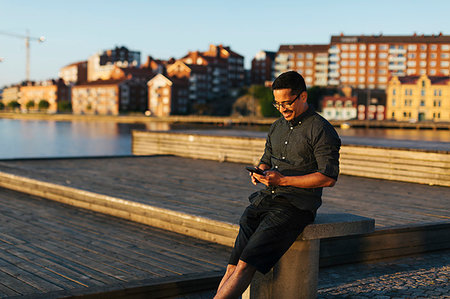 simsearch:6126-09204310,k - Man sitting on boardwalk using smart phone Photographie de stock - Premium Libres de Droits, Code: 6126-09267294