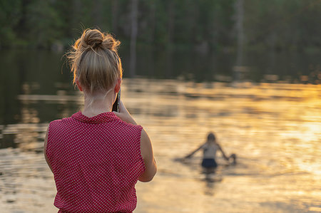 Woman photographing lake at sunset Stock Photo - Premium Royalty-Free, Code: 6126-09267204