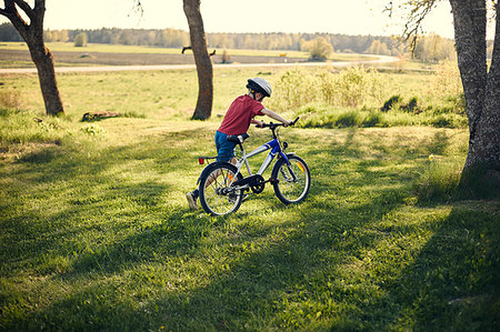 simsearch:6126-09267387,k - Boy pushing bicycle in on lawn Photographie de stock - Premium Libres de Droits, Code: 6126-09267379