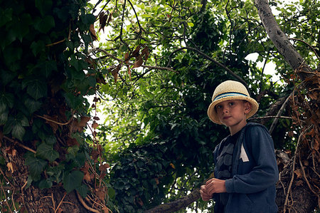 simsearch:6126-09267387,k - Boy wearing sun hat amongst tree branches Photographie de stock - Premium Libres de Droits, Code: 6126-09267387