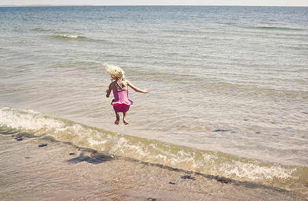 simsearch:6126-08635074,k - Girl jumping in wave on beach Stock Photo - Premium Royalty-Free, Code: 6126-09267398