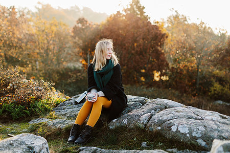 simsearch:6126-09266702,k - Woman holding mug sitting on rocks by bushes Fotografie stock - Premium Royalty-Free, Codice: 6126-09267333