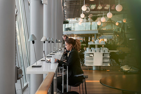 Woman using laptop in airport Stock Photo - Premium Royalty-Free, Code: 6126-09267733