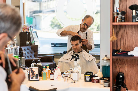 Reflection of barber cutting young man´s hair in mirror Stock Photo - Premium Royalty-Free, Code: 6126-09268203