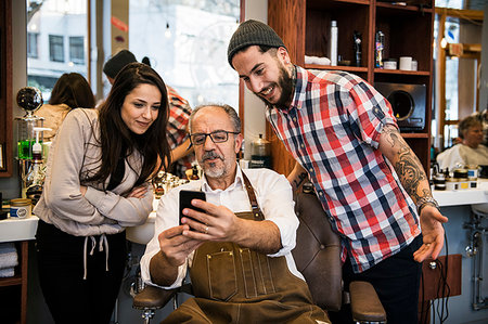 Barbers looking at colleague’s smartphone Stock Photo - Premium Royalty-Free, Code: 6126-09268236