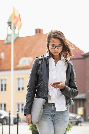 Young woman looking at her cell phone in Solvesborg, Sweden Stock Photo - Premium Royalty-Free, Code: 6126-09204582