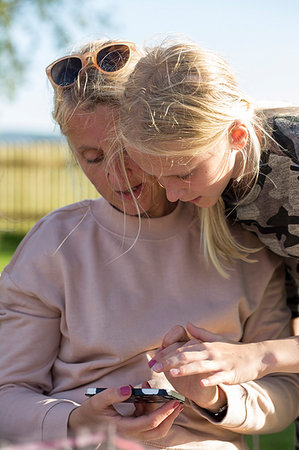 simsearch:6102-08388194,k - Mother and daughter looking at a cell phone outdoors in Sweden Foto de stock - Royalty Free Premium, Número: 6126-09204509