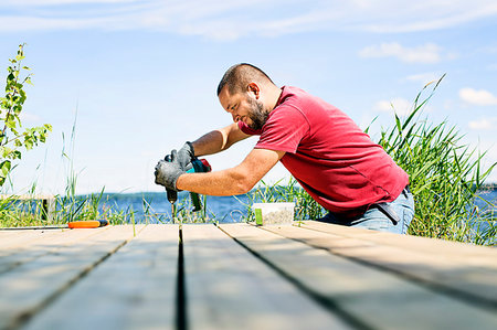 Mid adult man drilling a hole in a deck in Finland Stock Photo - Premium Royalty-Free, Code: 6126-09204675