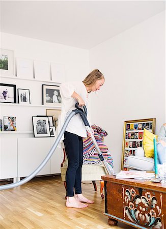 Young woman cleaning floor with vacuum cleaner at home Photographie de stock - Premium Libres de Droits, Code: 6127-08666158