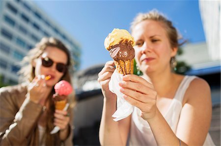 Woman holding melting ice cream while sitting with friend outdoors Photographie de stock - Premium Libres de Droits, Code: 6127-08666374
