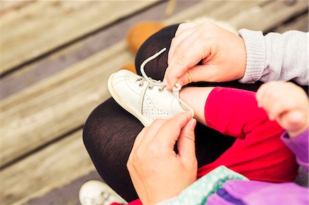 Low section of mother putting shoes on daughter outdoors Foto de stock - Sin royalties Premium, Código: 6127-08687767
