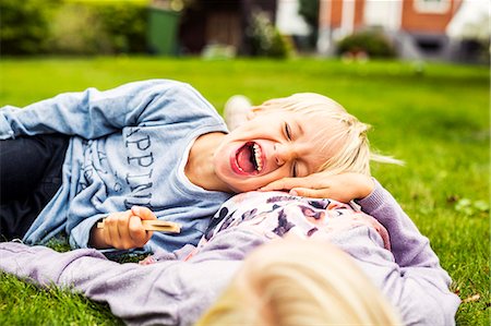 stomach - Cheerful boy lying on his sister's stomach in yard Stock Photo - Premium Royalty-Free, Code: 6127-08687766