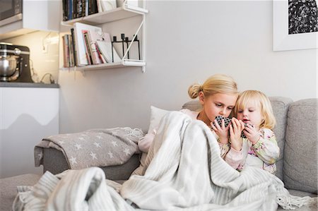 Sisters using mobile phone while relaxing on sofa at home Photographie de stock - Premium Libres de Droits, Code: 6127-08688270