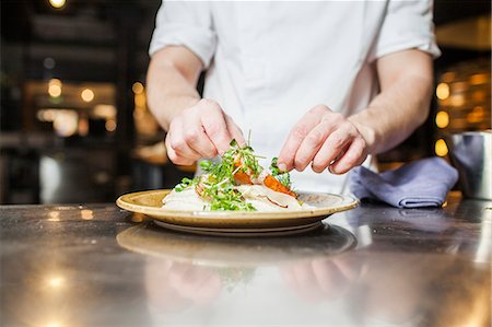 preparing food - Midsection of chef garnishing food in plate at counter Stock Photo - Premium Royalty-Free, Code: 6127-08689344