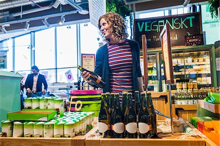 Smiling young woman holding bottle while standing in supermarket Stockbilder - Premium RF Lizenzfrei, Bildnummer: 6127-08704593
