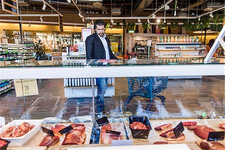 Man with girl in shopping cart while looking at meat in supermarket Photographie de stock - Premium Libres de Droits, Code: 6127-08704591