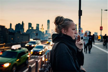 profil - Woman standing on bridge and smoking cigarette, cityscape in background Stockbilder - Premium RF Lizenzfrei, Bildnummer: 6127-08952538