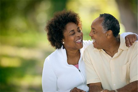 Happy mature man smiling at his wife as she affectionately puts her arm around his shoulders. Foto de stock - Sin royalties Premium, Código: 6128-08747454