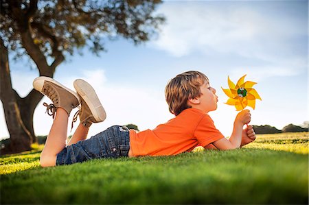 Happy young boy playing with a pinwheel in a park. Stock Photo - Premium Royalty-Free, Code: 6128-08747480