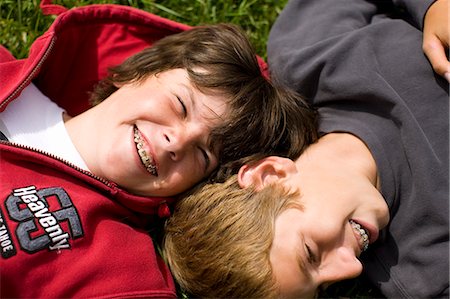 Portrait of two laughing boys lying on their backs with braces on their teeth. Stock Photo - Premium Royalty-Free, Code: 6128-08747529