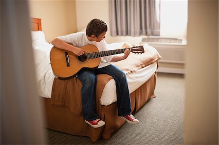 simsearch:6128-08728230,k - Boy practicing guitar in his bedroom Fotografie stock - Premium Royalty-Free, Codice: 6128-08747678