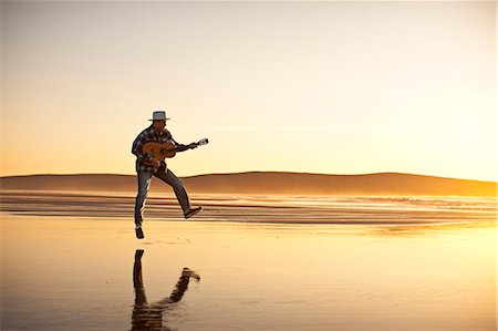 Man playing guitar on the beach Stock Photo - Premium Royalty-Free, Code: 6128-08747683