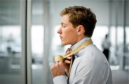 simsearch:6128-08747789,k - Young businessman tying his tie in his office. Stock Photo - Premium Royalty-Free, Code: 6128-08747799